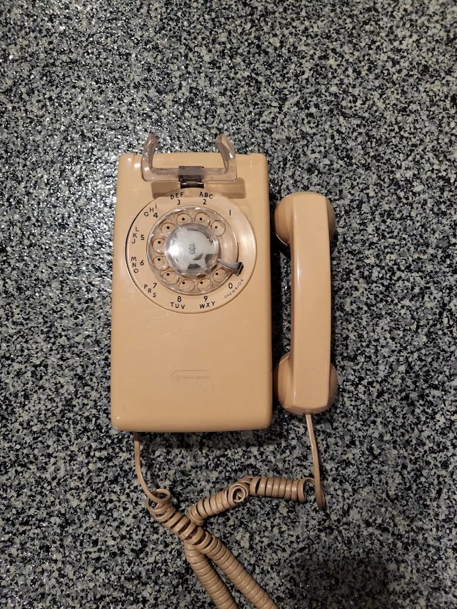 This vintage rotary phone 554 comes with its original handset and coiled cord, perfectly preserved in a beautiful beige color