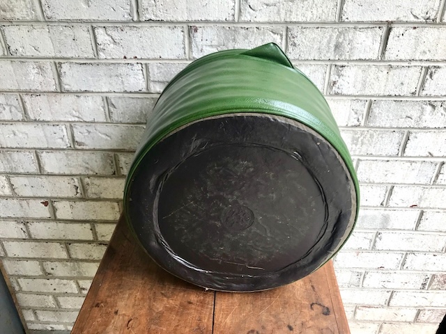 The underside of a vintage green ottoman pouffe, showcasing the wear and tear that comes with decades of service. This piece has certainly seen its share of footrests!