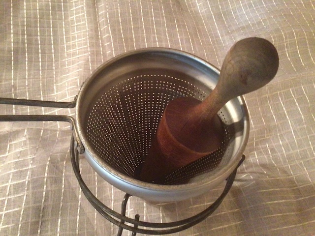 This vintage food strainer, featuring a robust wooden pestle, allowed home cooks to press ingredients through the metal mesh for a finer texture