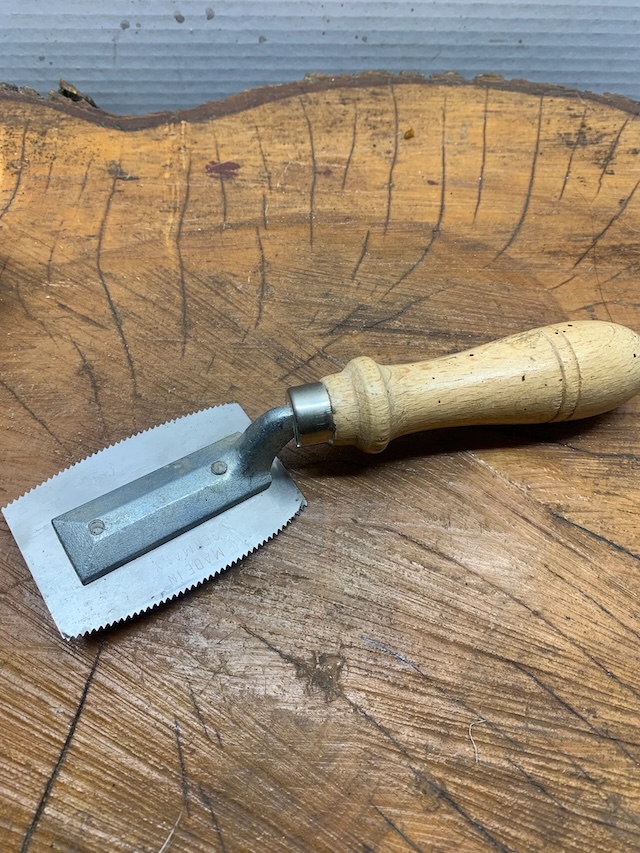 A well-maintained veneer saw with its traditional wooden handle and sharp-toothed blade, ready to be used for delicate tasks on wood veneers