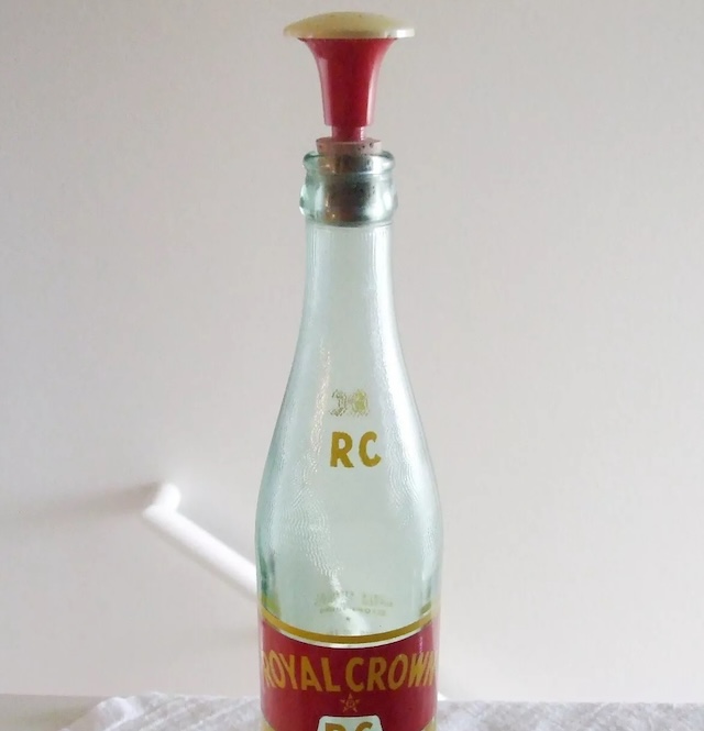 An old sprinkler bottle top attached to a vintage RC bottle, showing how everyday bottles were repurposed with this cap for ironing purposes