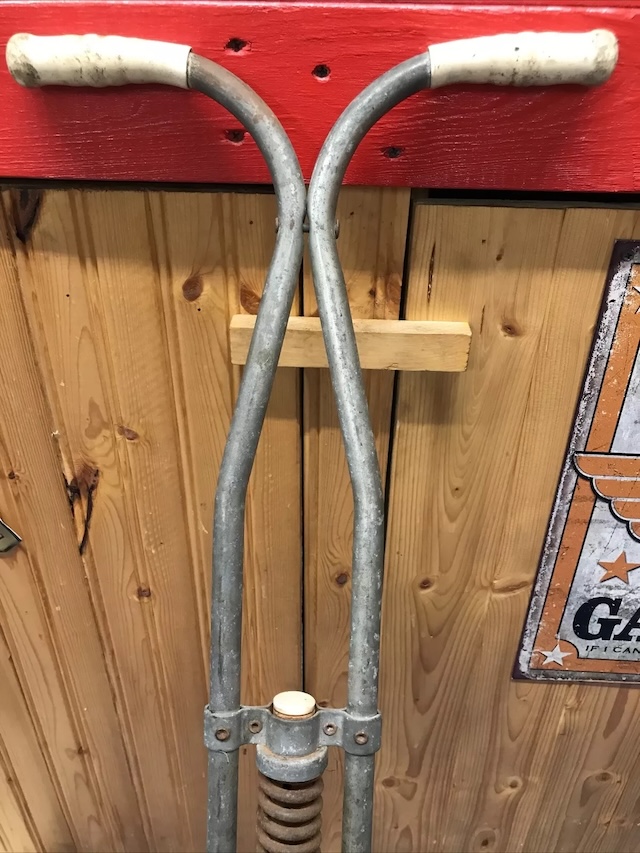 A classic pogo stick leaning against a vintage garage backdrop with signs and memorabilia. It feels like it's straight out of the 1960s, waiting for its next bounce session