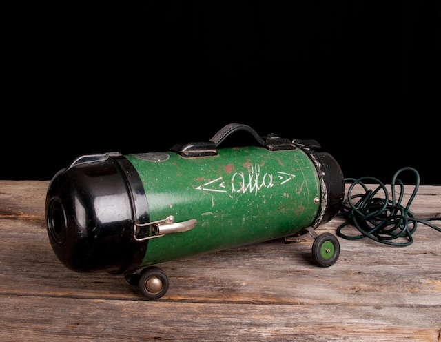 A striking green body and industrial black accents make this vintage vacuum a true relic, embodying both form and function