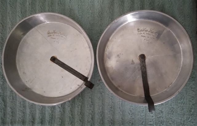 A pair of vintage slider cake pans, worn with use, sitting on a wooden surface, ready to create another baking masterpiece