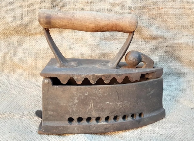 Another variation of the antique coal iron – this model features a solid wooden handle and vents at the base to allow the coal to breathe as it heated up, offering a glimpse into a once-common household chore