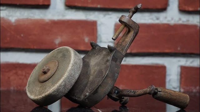 Though rusted and worn, this hand crank grinder still showcases the durability and craftsmanship of its design, symbolizing years of utility and service