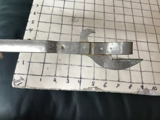 A classic can opener made from tempered steel, showcasing a simple yet efficient design for opening cans, commonly used in kitchens decades ago