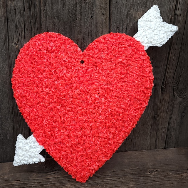 A vibrant heart-shaped decoration with an arrow through it, perfect for celebrating Valentine’s Day in a nostalgic way with melted plastic popcorn decorations