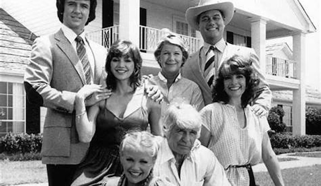 A vintage black-and-white photo of the iconic Dallas cast, featuring the Ewings in front of their legendary Southfork Ranch