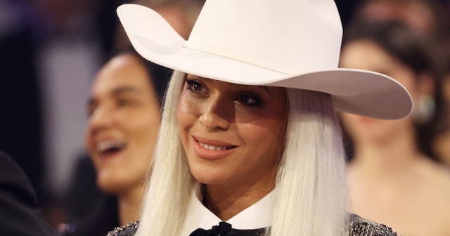 Beyoncé at a major event, donning a white cowboy hat, challenging genre expectations with her crossover appeal