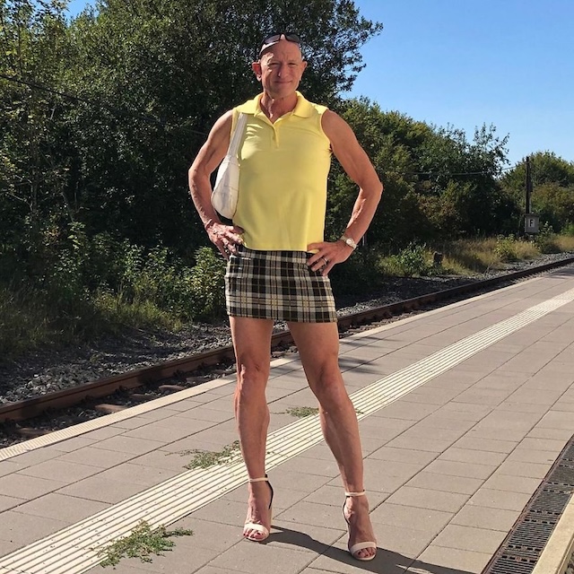 Rocking a yellow polo and plaid skirt with heels, confident and stylish at the station