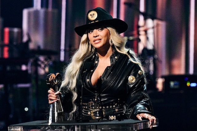 Beyoncé accepting an award in a bold black outfit, showcasing her unapologetic style and artistry