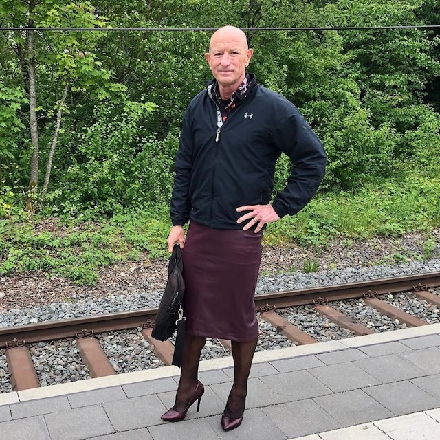 Striking a confident pose at the station in a maroon skirt, black jacket, and heels, blending casual and bold