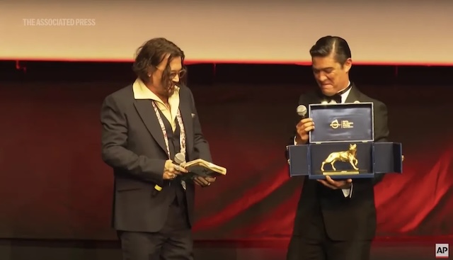 Depp receives the prestigious Lifetime Achievement Award at the Rome Film Festival, holding the award with a grateful smile. A significant moment in his career, recognized by fellow actor Riccardo Scamarcio.