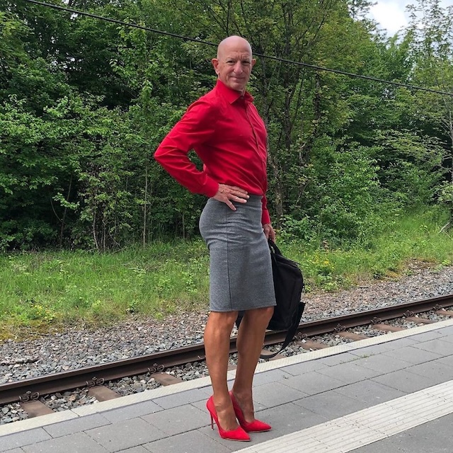 In a bold red shirt and gray skirt, Mark Bryan commands attention while waiting at the train station