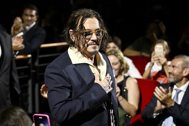 Depp places a hand over his heart as the audience applauds him, showing his appreciation and humility. His fans capture this memorable moment on their phones, adding to the night’s warm atmosphere