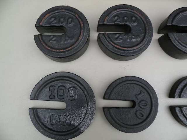 A collection of vintage scale weights with distinctive markings, reflecting the quality craftsmanship of their time