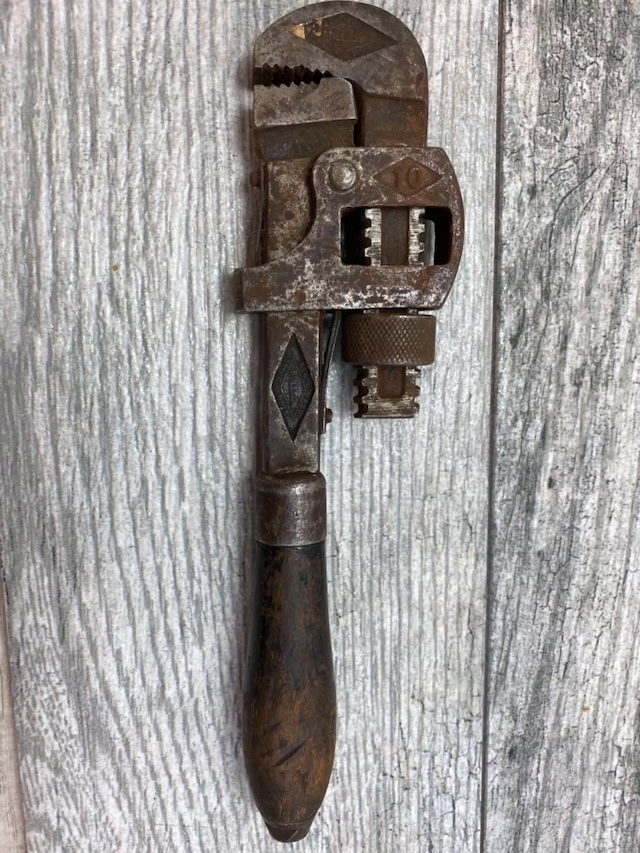 A close-up of a Stillson wrench, showing off the heavy-duty metal head and teeth—perfect for gripping pipes and bolts in any condition