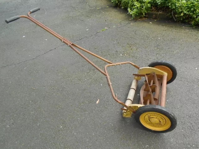 The sturdy handles and intricate mechanics of this vintage reel mower reflect the craftsmanship of a bygone era, making lawn maintenance a unique experience