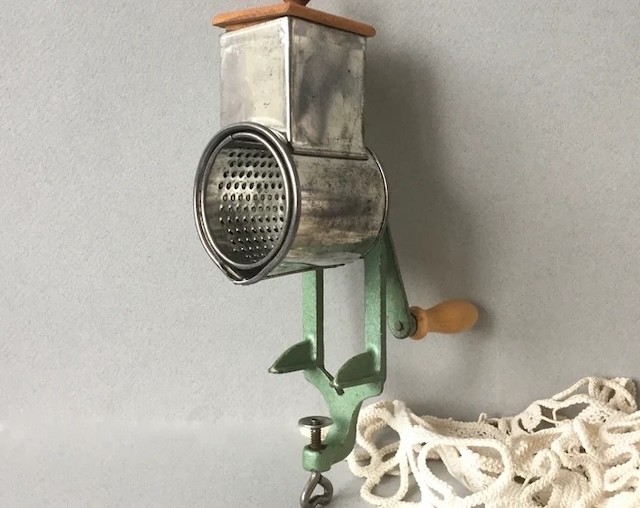 Another angle of the vintage hand-cranked nut grinder, highlighting its vibrant color and the craftsmanship that went into making kitchen utensils of yesteryear