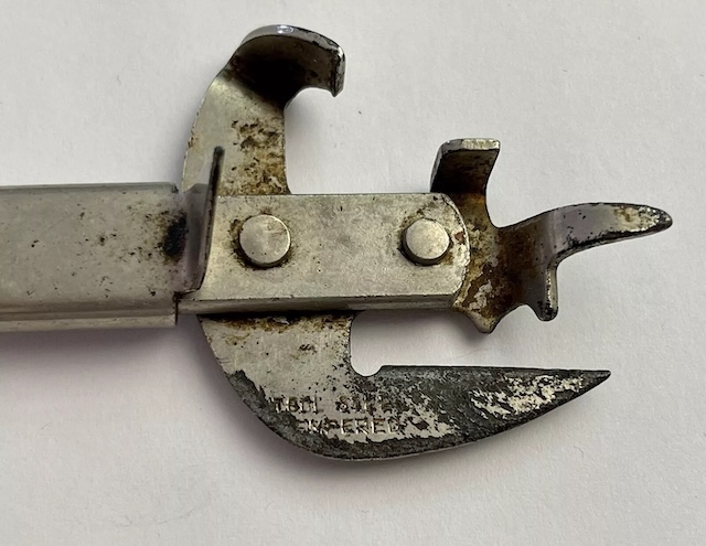 Close-up of the iconic vintage can opener, with its aged yet functional blade and ergonomic wooden handle