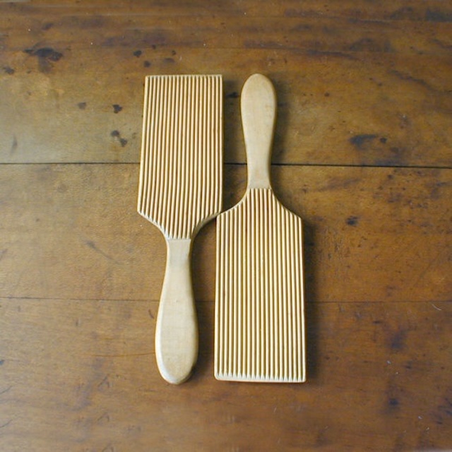 Vintage butter paddles placed on a wooden table, highlighting their textured grooves and ergonomic handles. This set, a testament to a simpler time, was once a vital tool for dairy processing