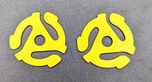 Pair of classic yellow 45 RPM record adapters, showcasing their iconic design that enabled seamless play on turntables