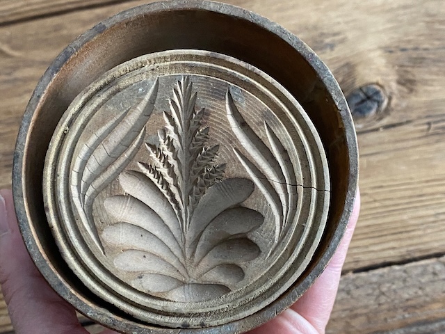 This antique carved wood butter mold likely brought charm and beauty to kitchen tables in the past, showcasing timeless artistry