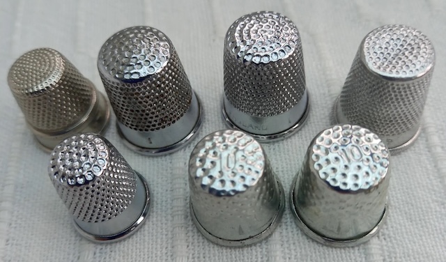 An array of shiny metallic vintage thimbles that reflect a bygone era of sewing and craftsmanship, each telling a story of its own