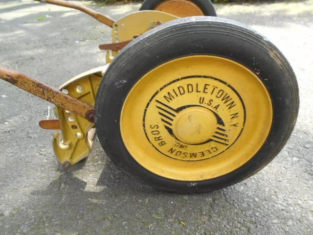 The rear wheels of this vintage reel mower tell a story of many seasons spent trimming grass and maintaining beautiful landscapes