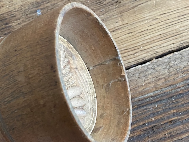 A close-up of the detailed carving on this antique carved wood butter mold, revealing its unique design that would have left a lasting impression on butter made by hand