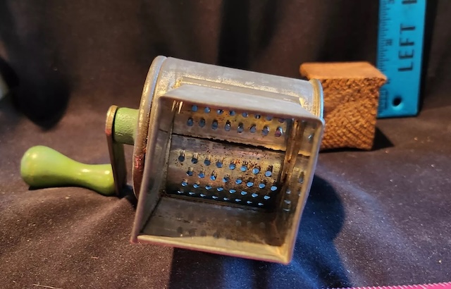 The vintage hand-cranked nut grinder with the lid removed, revealing the grinding chamber. This image captures the essence of traditional kitchen tools that were built to last and serve multiple generations