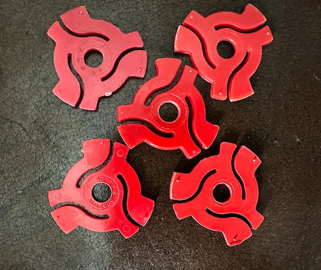 A collection of red 45 RPM record adapters laid out, emphasizing the range of colors that once added flair to turntables