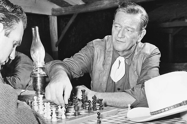 John Wayne enjoys a game of chess, revealing a more personal side of the legendary actor.