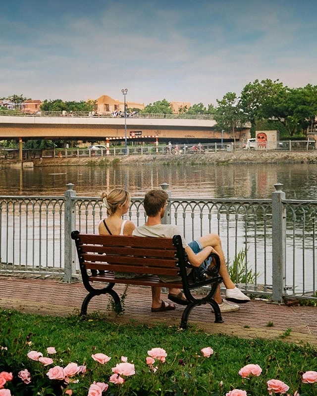 A serene image of a couple on a park bench overlooking the water, basking in the tranquility of a simple yet beautiful date