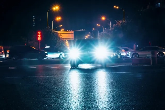 A city intersection illuminated by overly bright headlights, emphasizing the issue for urban drivers