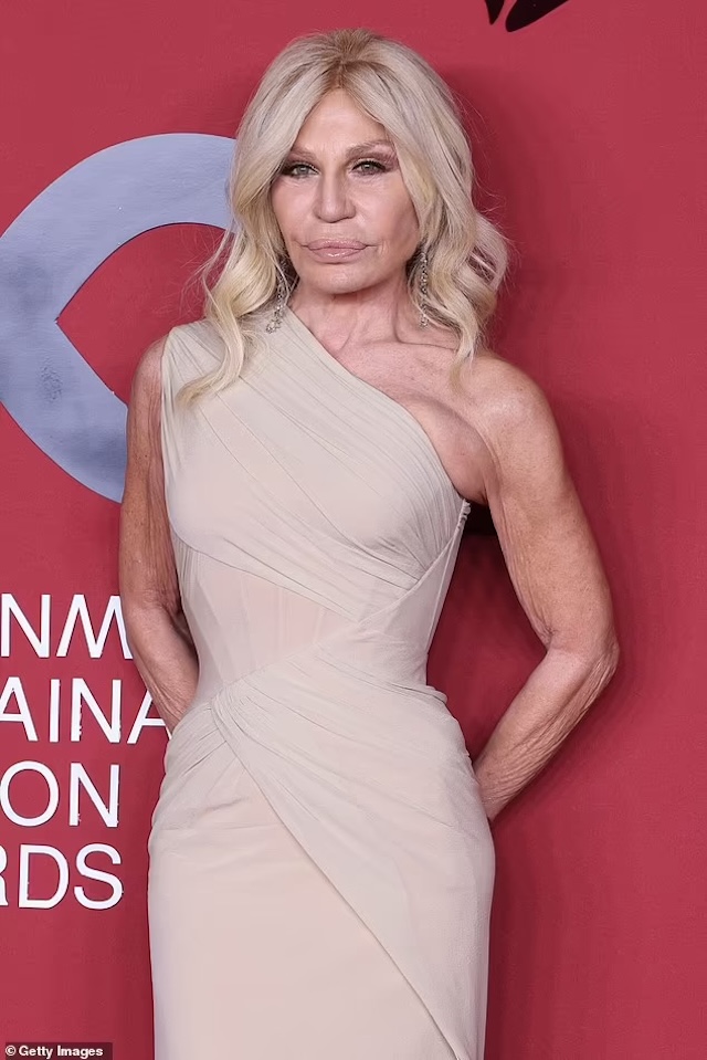 A poised and elegant Donatella strikes a graceful pose in a stunning embellished dress at a prestigious event