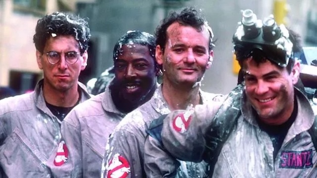 The iconic Ghostbusters team—Egon Spengler, Winston Zeddemore, Peter Venkman, and Ray Stantz—posing together during one of their memorable on-set moments, covered in ectoplasmic goo after a job well done