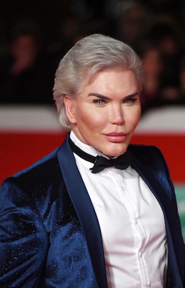 Rodrigo Alves, known for his transformation to look like a human Ken doll, poses at a public event with a confident, polished appearance