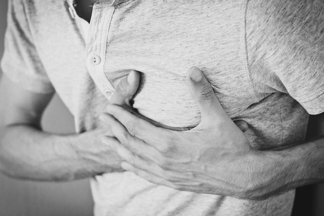 A person clutching their chest, experiencing symptoms associated with heart distress