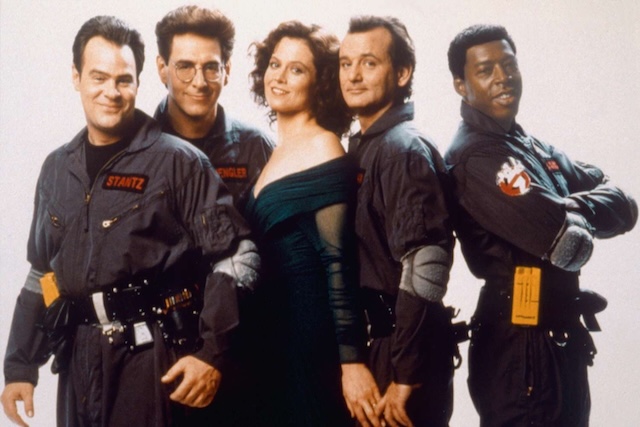 The Ghostbusters team, including Sigourney Weaver as Dana Barrett, all suited up in their signature jumpsuits for a promotional photo. Their dynamic onscreen presence remains unforgettable