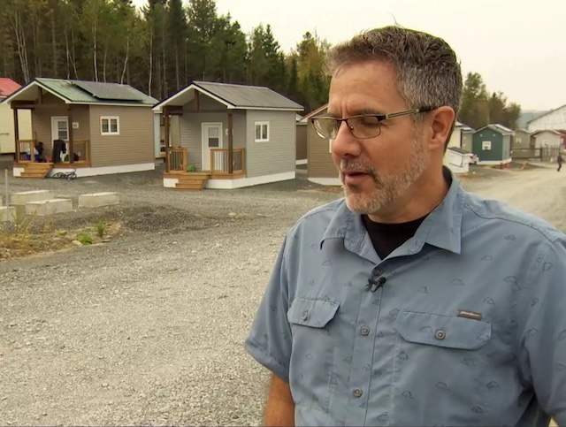 Marcel LeBrun, the millionaire philanthropist behind the 12 Neighbours project, stands proudly in front of some of the newly built homes