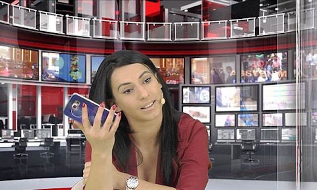  A relaxed moment on set, Enki takes a break from the news broadcast as she answers a call, offering a glimpse of her natural, approachable persona