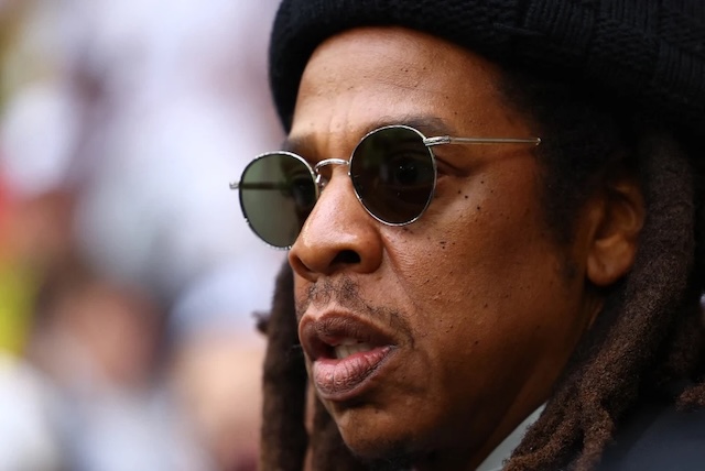 Jay-Z seen at a public event, sporting a beanie and sunglasses, exuding confidence and calm