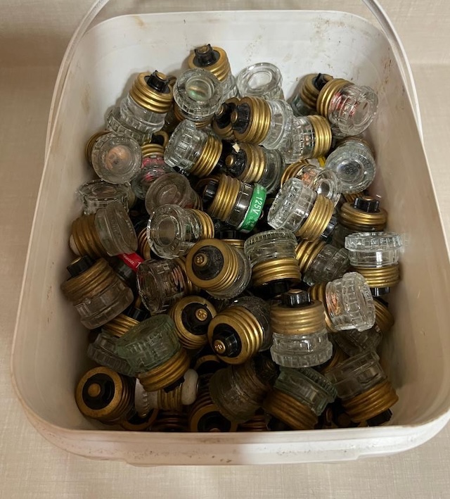  A box filled with assorted vintage glass fuses from different time periods, showcasing their variety in sizes and designs