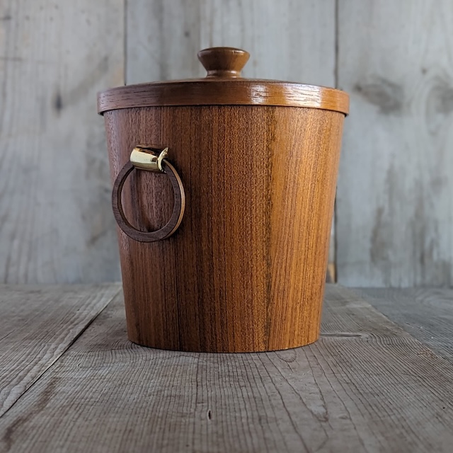 A minimalist yet functional vintage ice bucket, its smooth wood texture and loop handle evoke a cozy, retro vibe