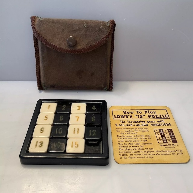 A retro 15 Puzzle with its original brown leather pouch and an instruction card highlighting its countless variations, emphasizing its portability