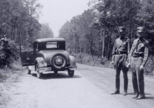 Two police officers survey the site of Bonnie and Clyde's ambush along Louisiana State Highway 154 near Sailes