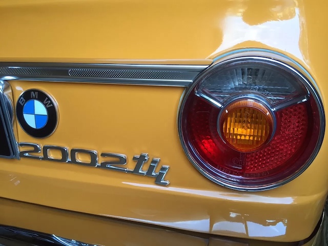 The rear end of a BMW 2002 Tii Touring, with its unmistakable badge and tail light design, emphasizing its functional yet stylish attributes