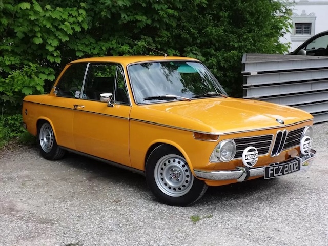 The iconic orange BMW 2002 Tii with rally lights, a true representation of the car’s racing pedigree, including its historic win at the 1970 Nürburgring 24 Hours